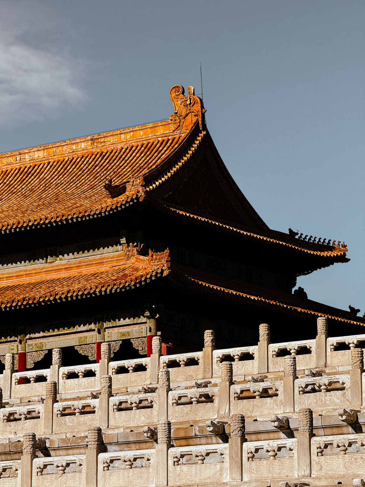 Golden glazed-tile roof and marble balustrade of the Forbidden City against a clear blue sky