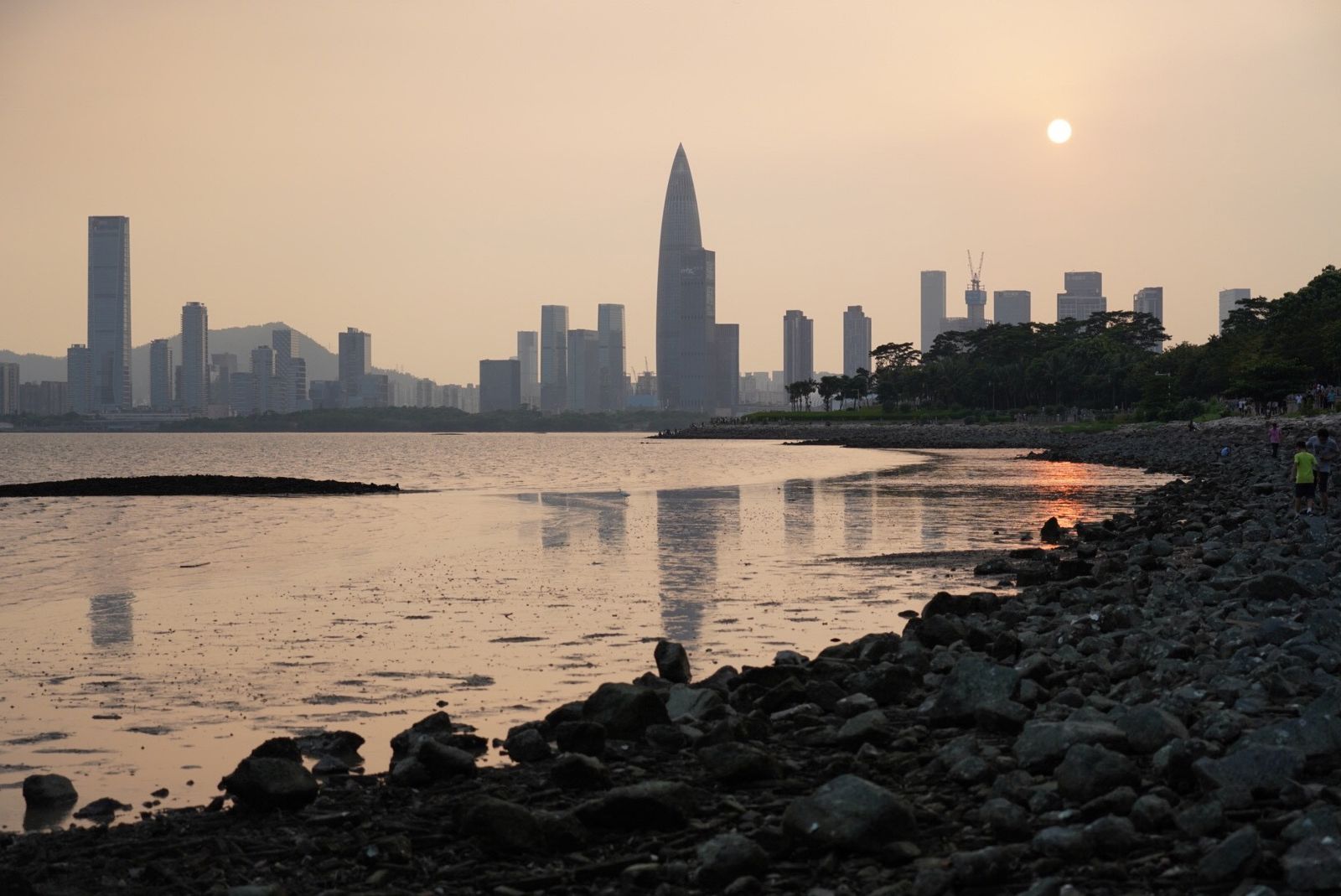 Shenzhen skyline with its landmark tower silhouetted at sunset, reflected in the water