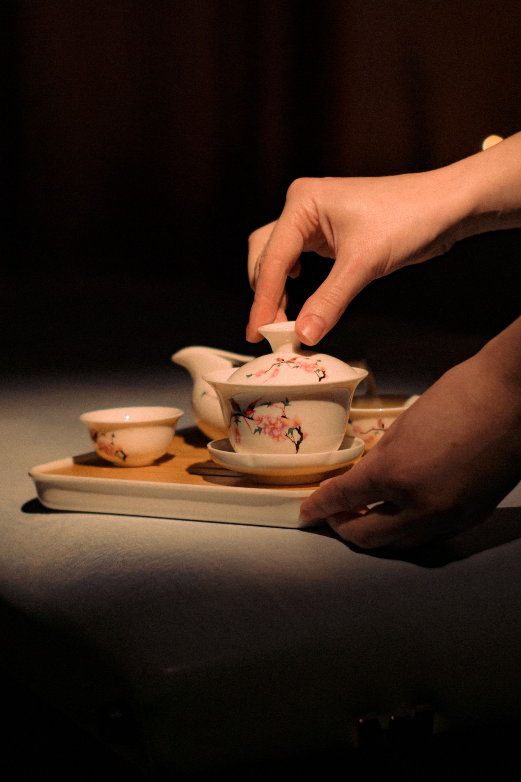 Hands holding a ceramic teapot and cup
