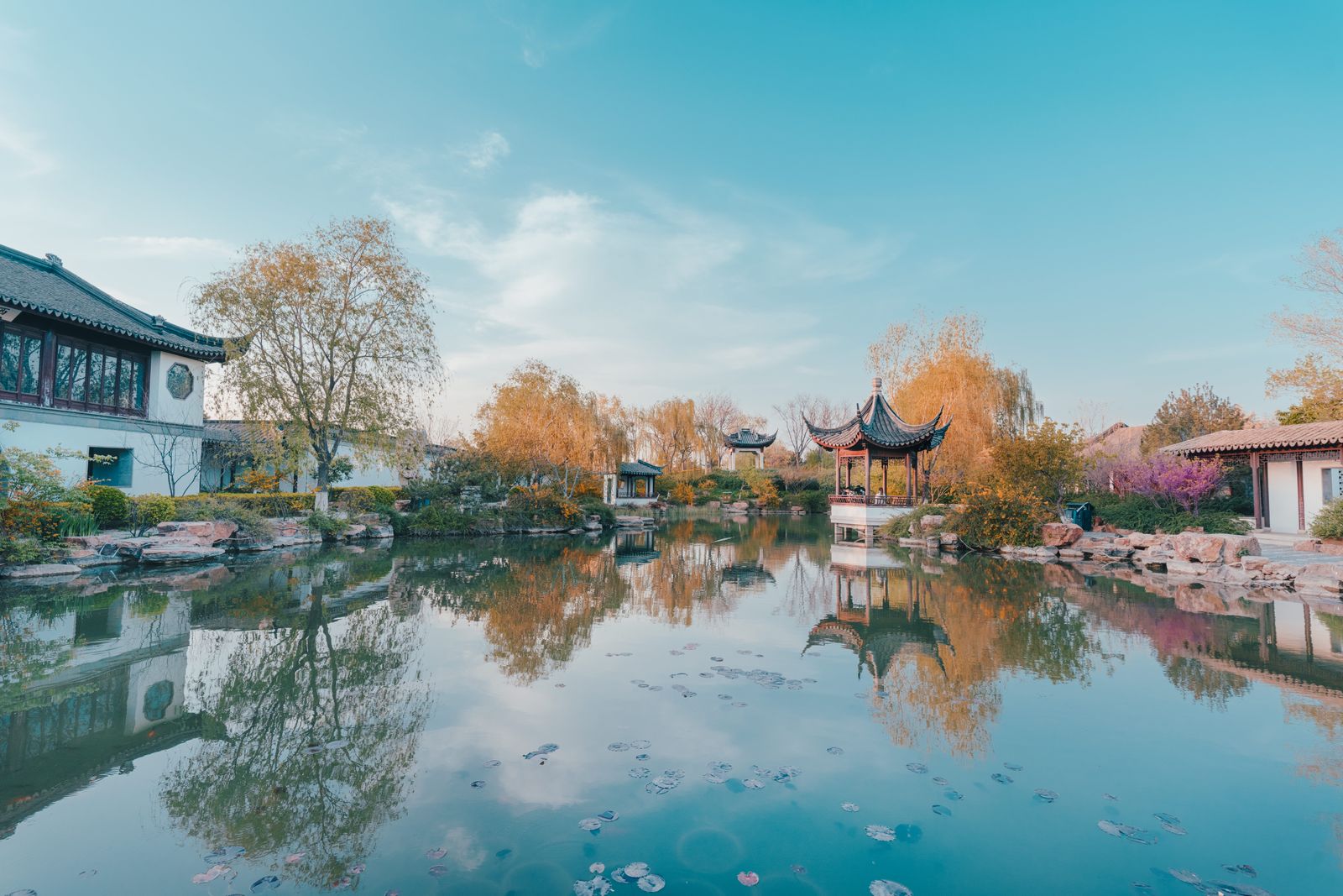 Autumn reflection of traditional Chinese pavilions in a serene garden pond at the Garden of Cultivation, one of Suzhou's classical gardens